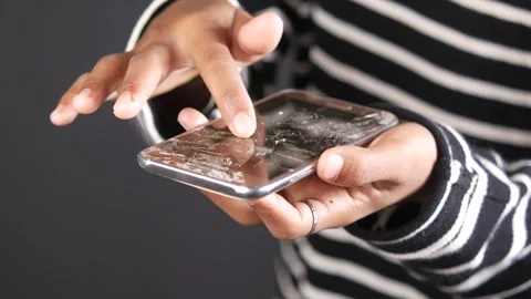 Hand touches broken smartphone screen showing cracks and damage. Stock-Footage 332777513