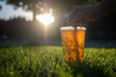 Hand touching bubble tea straw on lawn Stock Photos