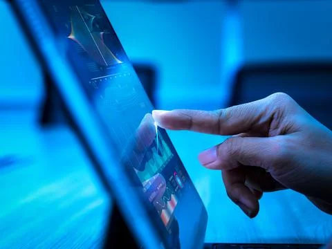 Hand touching digital tablet with data visualization graphs, representing b.. Stock Photos