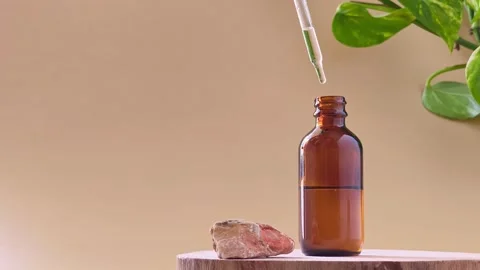 Hand touching dropper on amber glass bottle near natural stone on wood slice. Stock Footage 337100982