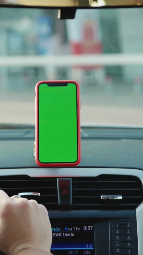 A hand is touching a green screen smartphone while sitting inside a car during Stock Footage 314169880