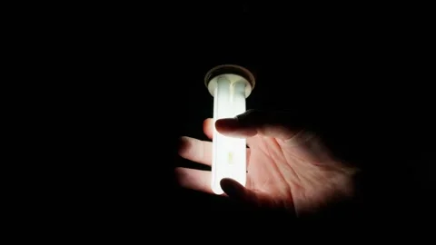 Hand Touching Illuminated Energy Saving Light Bulb in Darkness 動画素材 334133961