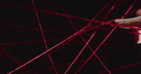 Hand touching a net of stretched red wool threads on a black background. Concept Stock Footage 312146508