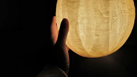 Hand touching a paper lantern lamp in the darkness Stock Footage 230032349