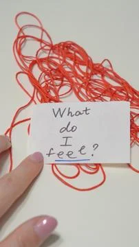 Hand touching paper note with question about feelings, red thread background Stock Photos
