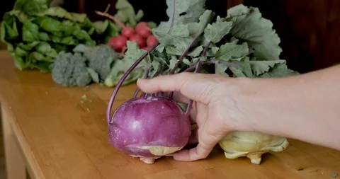 Hand touching a purple kohlrabi vegetable on a wooden cutting board Stock Footage 109073448