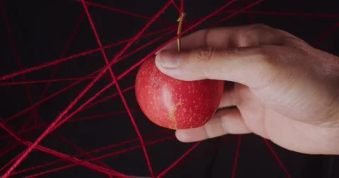 Hand touching red apple hanging inside net of stretched red woolen threads on Stock Footage 312146563