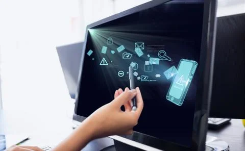 Hand is touching the screen of a computer with a pen against office background Stock Photos