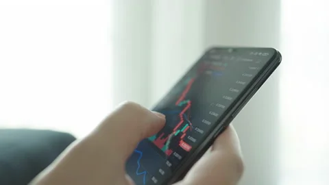 Hand touching screen mobile phone investing stock market application. Financi Stock Footage 183764471