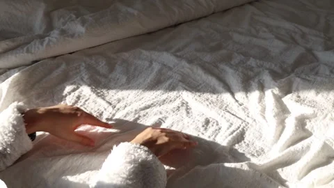 Hand touching sheets in bed, with sunlight creating shadows. Stock Footage 326989635