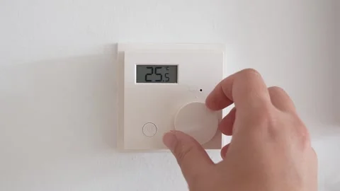 Hand touching smart thermostat, increasing the temperature on a digital device 库存影片 310569923