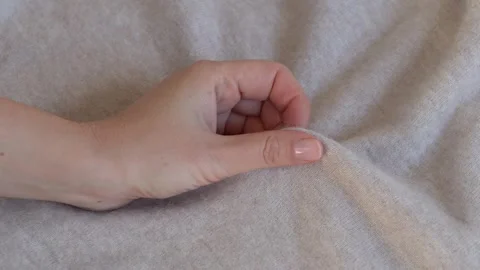 Hand touching soft textile emphasizing comfort and tactile quality. Suitable for Stock Footage 332875999