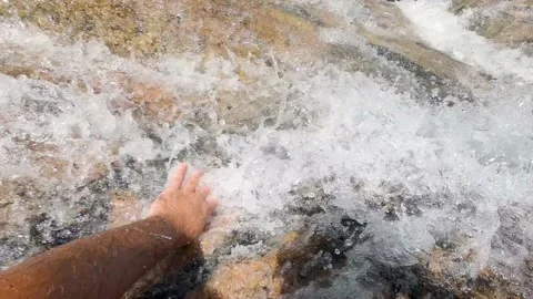 Hand touching the stream of water from the waterfall Stock Footage 168885934