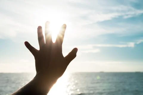 Hand touching sun during sunset background success, peace, freedom and hope c Stock Photos