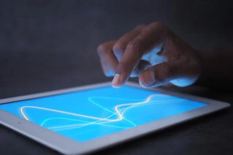 A hand is touching a tablet screen showing financial chart. Stock Photos