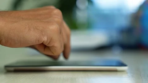 Hand Touching Tablet Screen on Wooden Table, Close-up of a hand touching a .. Stock Footage 346484207