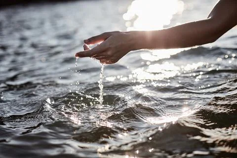 Hand Touching Water with Sunlight Reflection on Peaceful Lake Surface Stock Photos