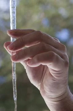 Hand touchs sharp icicles hanging on the edge of the roof Stock Photos