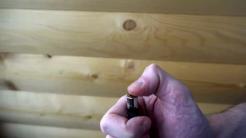 Hand tries to light the lighter on the background of wooden wall Stock-Footage 74751625