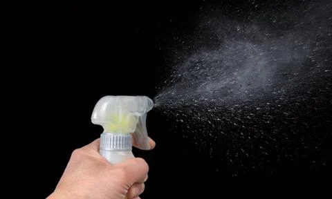Hand triggering a sanitizing bottle  on black background Foto stock
