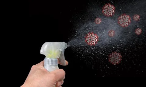Hand triggering a sanitizing bottle at COVID-19 viruses on black background Foto stock