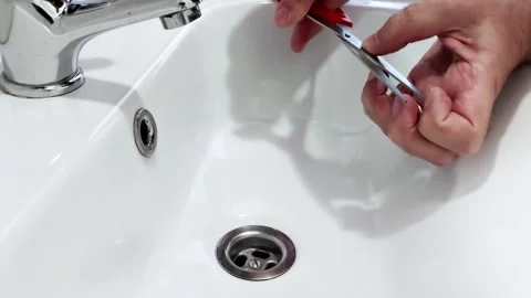 Hand Trims Nails Over White Sink: Clean Grooming in Soft Lighting Stock-Footage 315019678