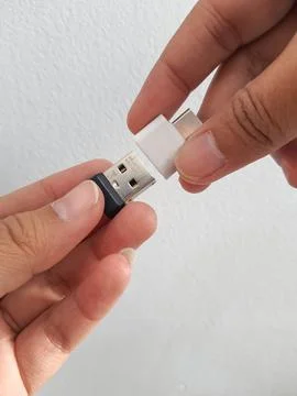 A hand is trying to insert a small flask disk into a Adapter USB Type C to US Stock Photos