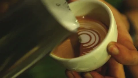 A hand trying to pouring steamed milk to hot coffee to making latte art. Vídeo Stock 334650152
