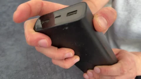 Hand trying to power on discharged power bank close up, empty external battery Stock Footage 337120995