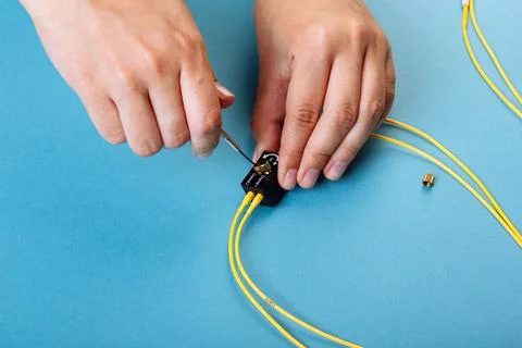 Hand tune an variable optic attenuator with a screwdriver. Blue background Stock Photos
