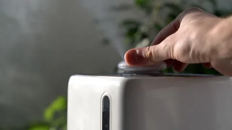 Hand turn on aroma oil diffuser on the table at home, steam from the air Stock Footage 150189271