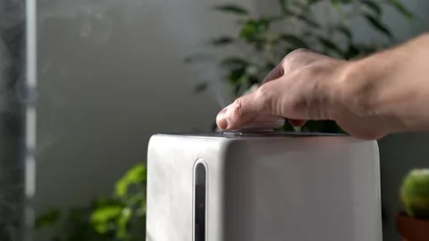 Hand turn on aroma oil diffuser on the table at home, steam from the air Stock Footage 150216053