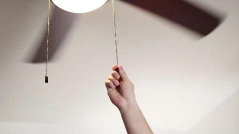 Hand turn on the light of fan ceiling in the living room Stock Footage 236595470