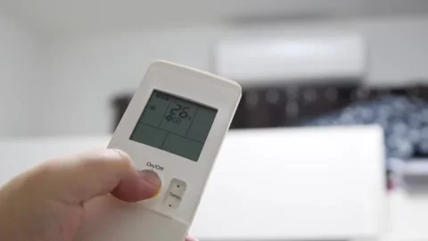 Hand turning on air conditioner remote to cool down the living room or space.  Vidéo 158670371