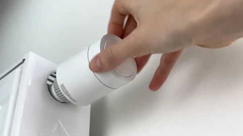 Hand turning on central heating radiator battery using a thermostatic valve.. Stock Footage 346156625