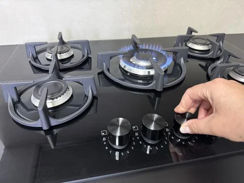 Hand turning the control knob on a modern gas stove Stock Photos