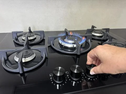 Hand turning the control knob on a modern gas stove Stock Photos