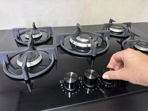 Hand turning the control knob on a modern gas stove Stock Photos