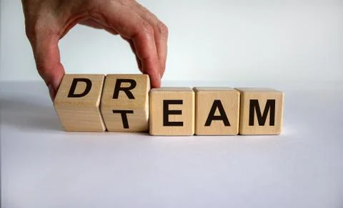 Hand is turning cubes and changes the word 'dream' to 'team'. Beautiful white Stock Photos