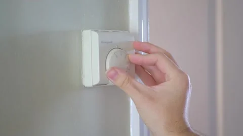 Hand Turning Down Central Heating Thermostat Stock Footage 303660934