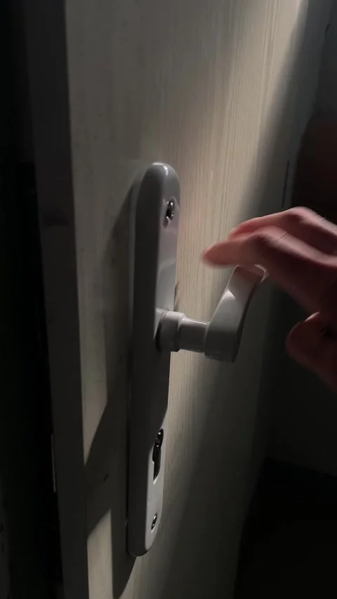 Hand turning key into lock beside white lever handle on light wood interior Vidéo 341664389