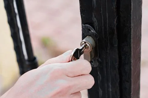 Hand Turning Key In Metal Gate Lock Foto stock