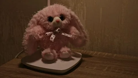 Hand turning off light next to pink plush bunny toy on nightstand, bedtime s Stock Footage 346306045