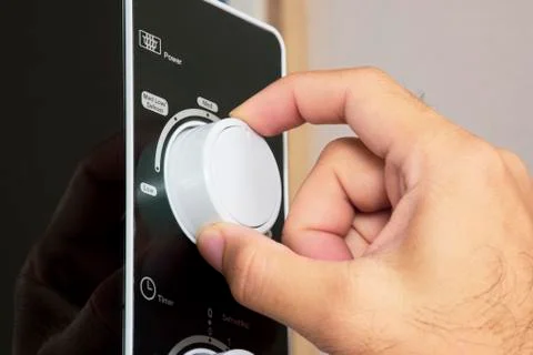 Hand is turning the mode selector of microwave oven knob 스톡 사진