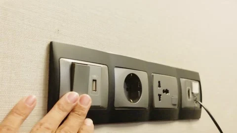 Hand turning on modern electrical wall switch next to power outlets and USB port 스톡 동영상 344092155