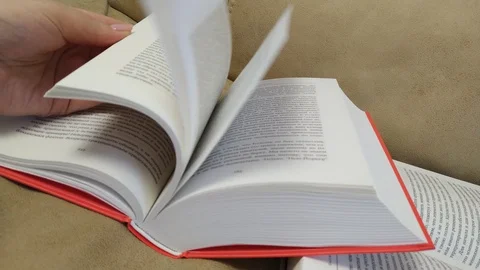 Hand turning pages of a book. Reading a hardback book. Home schooling. 4K. Stock Footage 128222573