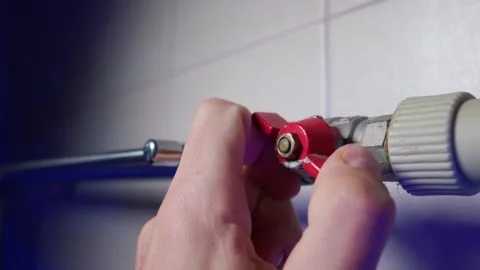 Hand Turning Red Ball Valve Handle to Shut Off Central Heating Pipe in House Stock Footage 339211822