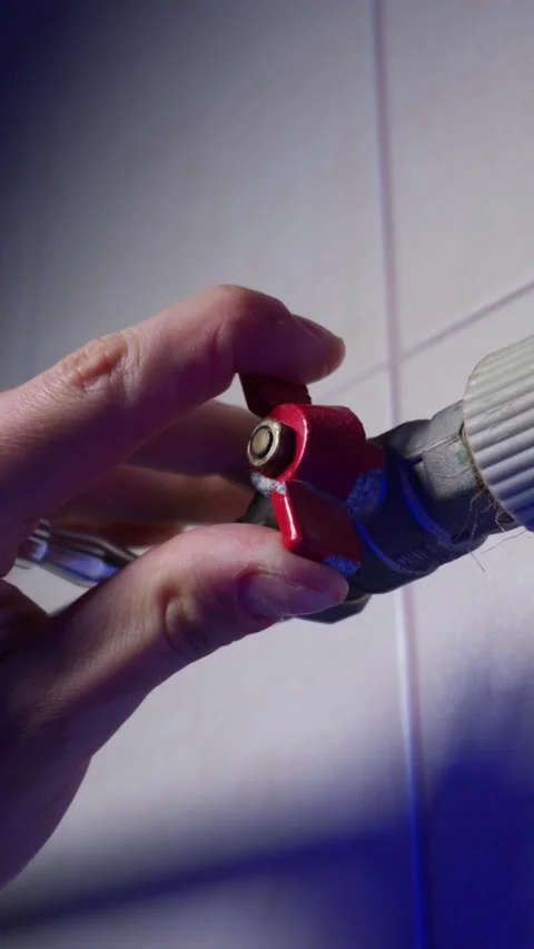 Hand Turning Red Ball Valve to Open Position on Water Supply Pipeline Stock Footage 339213656