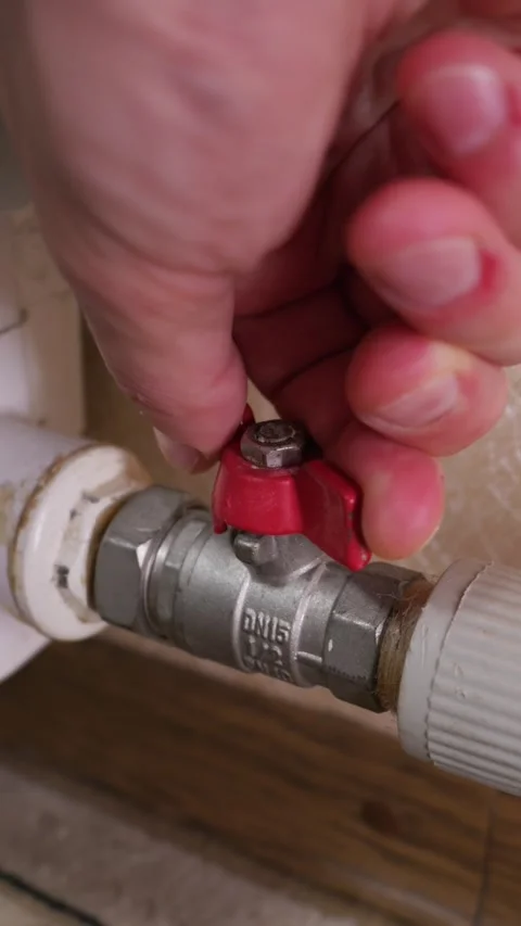 Hand Turning Red Ball Valve to Shut Off Home Heating Pipe Water Supply Stock Footage 339213795