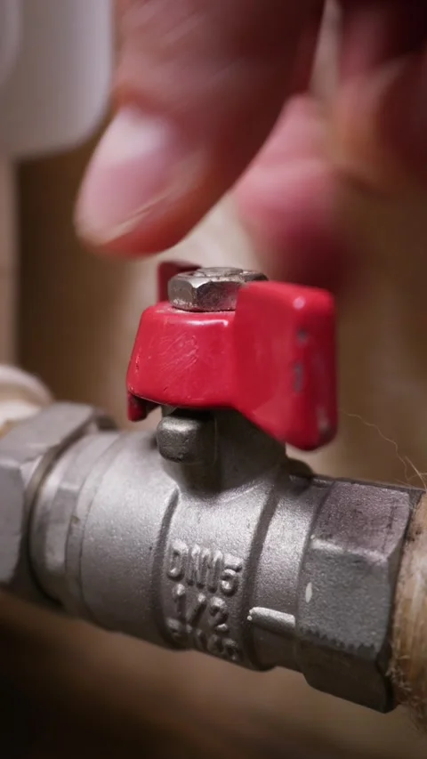 Hand Turning Red Ball Valve Handle to Shut Off Water or Heating Supply Pipe Stock Footage 339214043